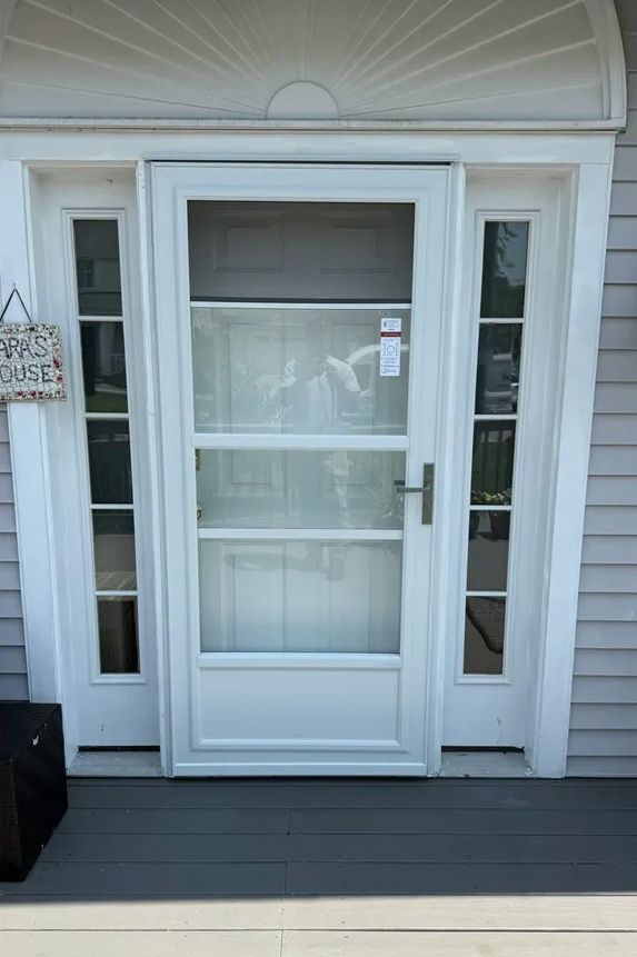 White screen door with side panels, on a porch.