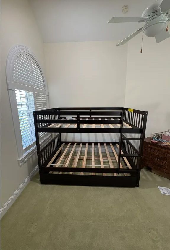 Dark brown bunk bed in a bedroom with a window and a ceiling fan.