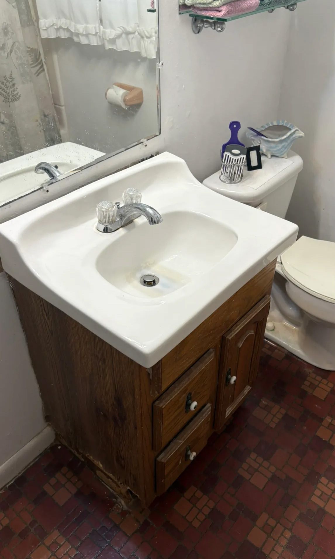 Bathroom with a white sink on a wooden cabinet, toilet, and mirror.