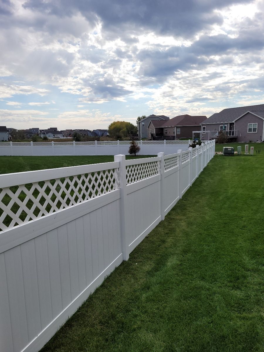 A white fence surrounds a lush green lawn in a backyard.