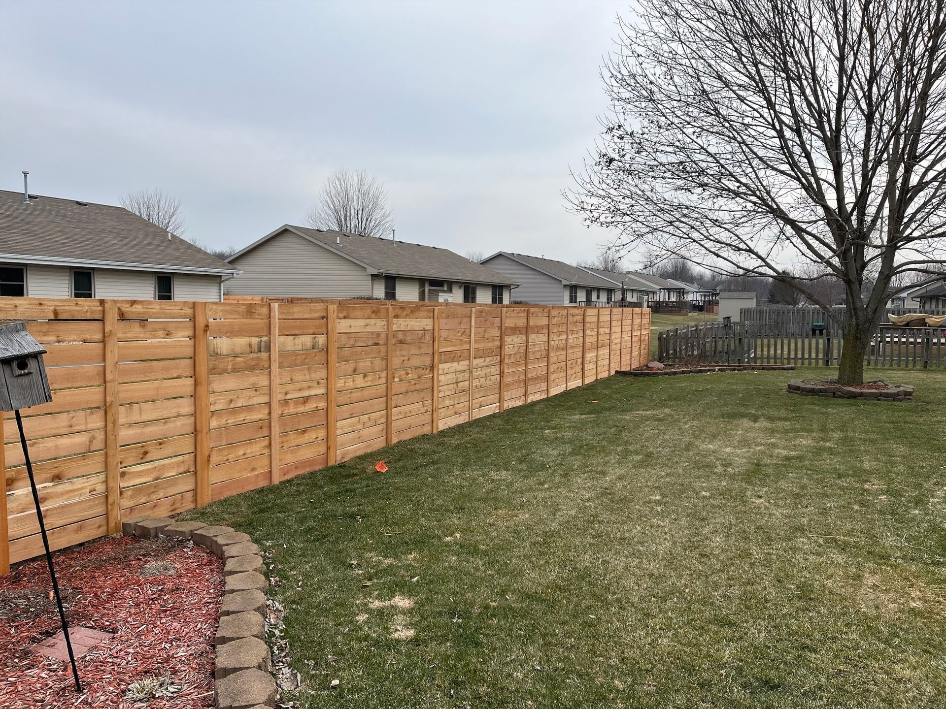 A wooden fence is in the backyard of a house.
