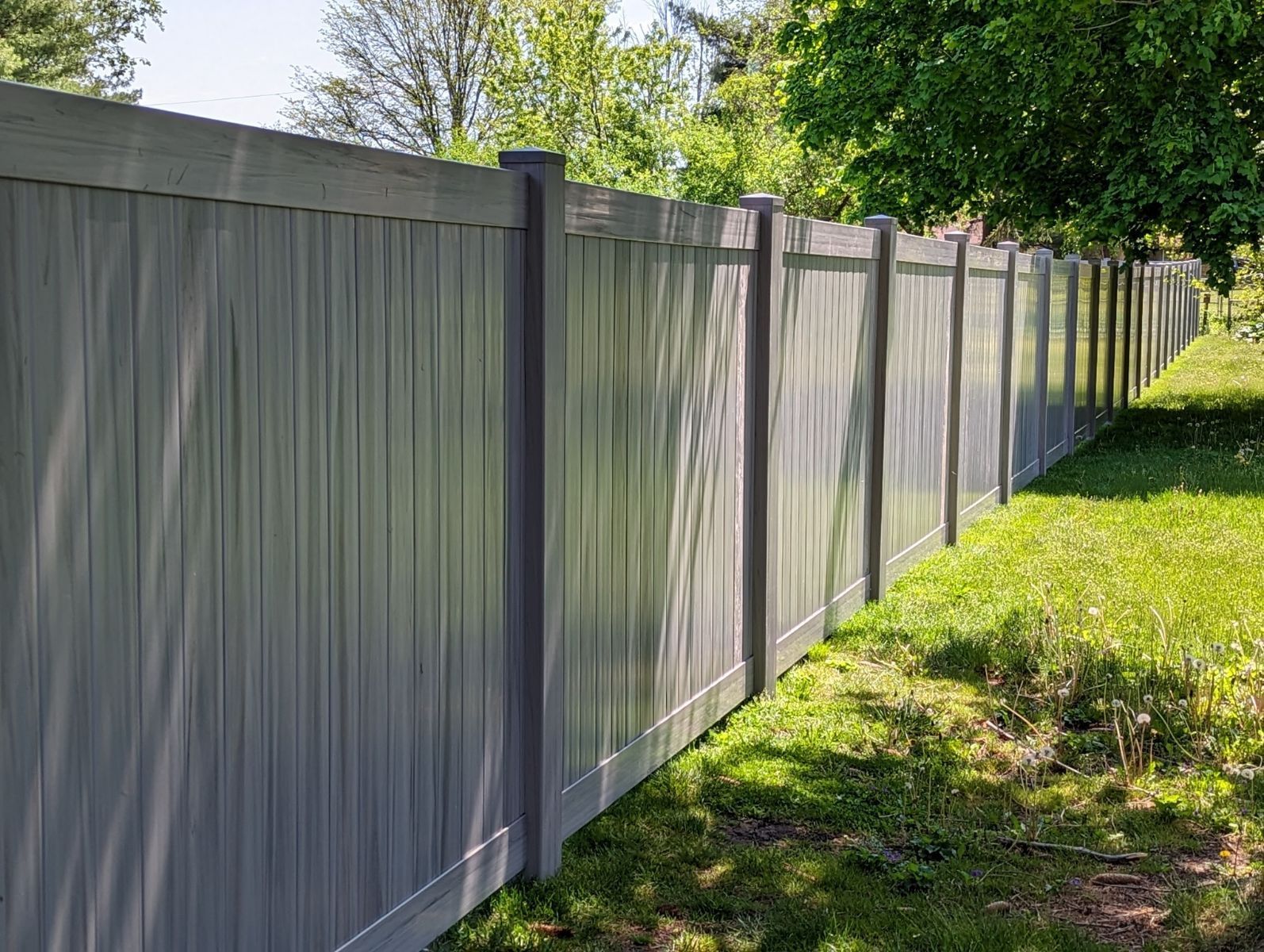 A gray wooden fence is sitting in the middle of a lush green field.