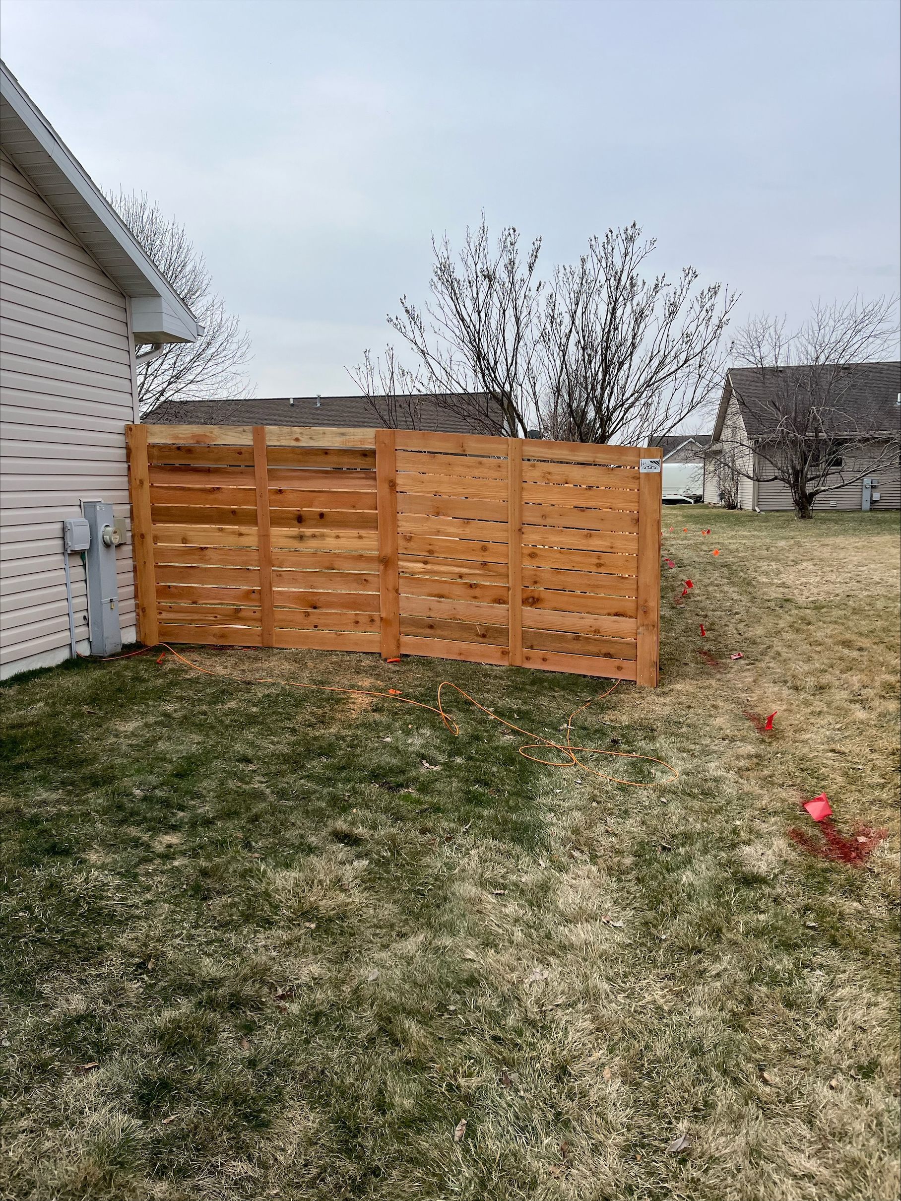A wooden fence is in the backyard of a house.