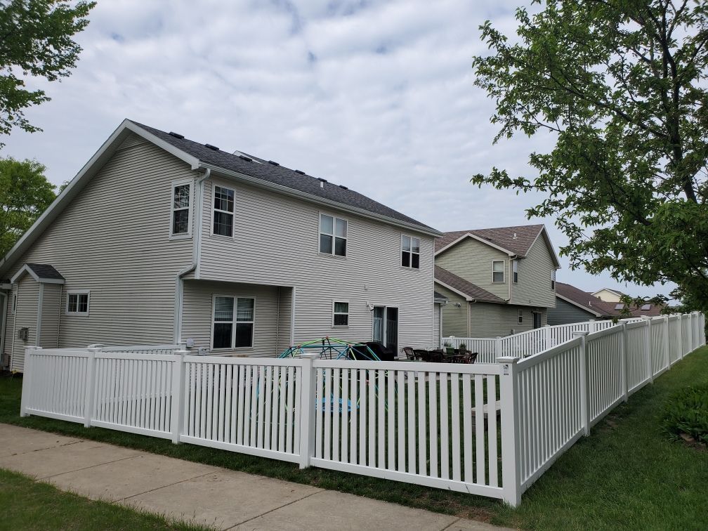 A white fence surrounds a house in a residential area.