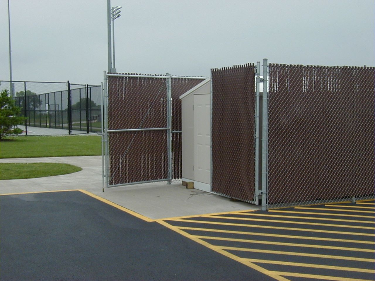 A chain link fence surrounds a building in a parking lot