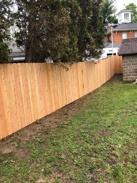 A wooden fence is surrounding a lush green yard.