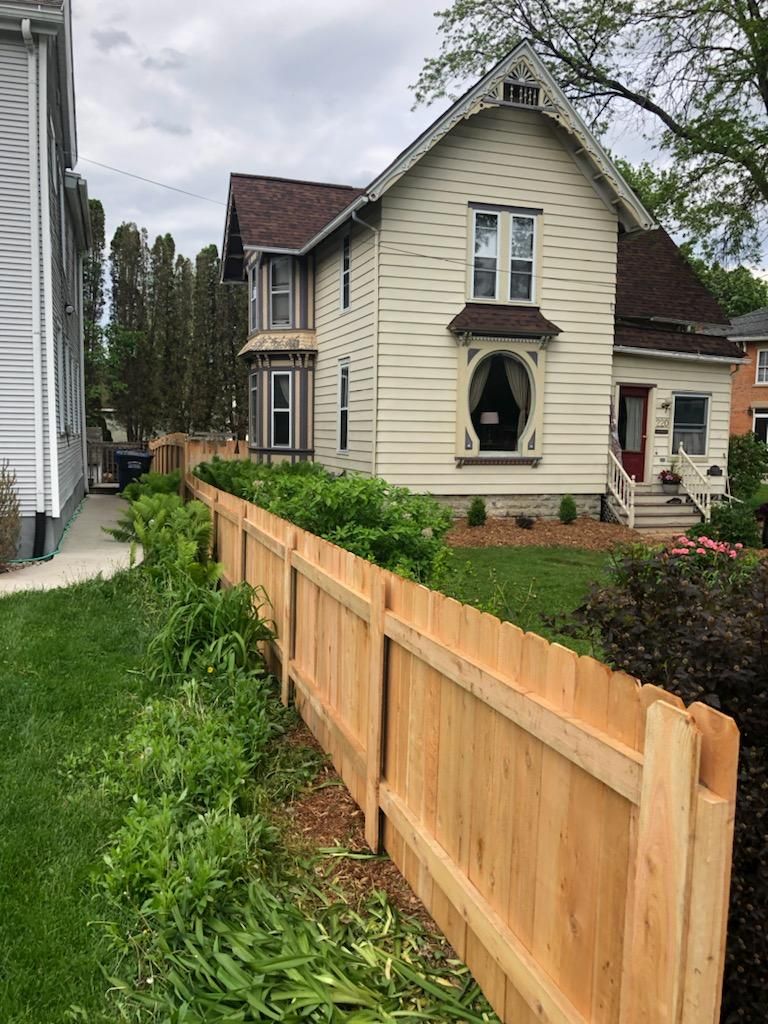 A wooden fence is in front of a house.