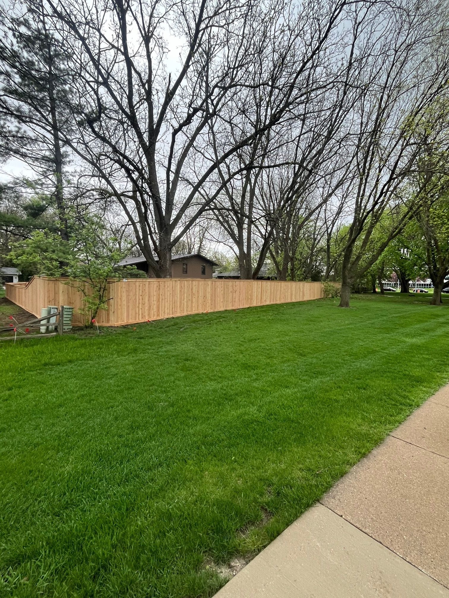 A wooden fence surrounds a lush green yard.