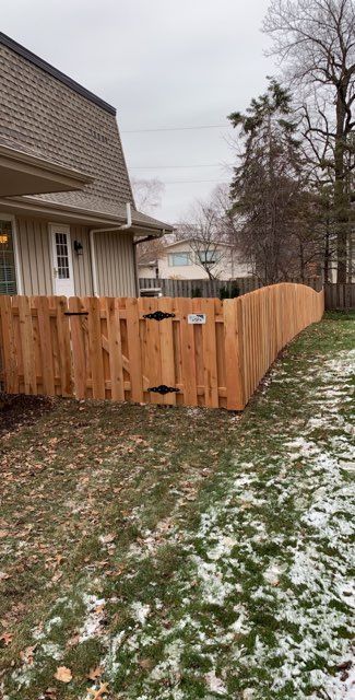 A wooden fence with a gate in the backyard of a house.