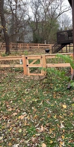 A wooden fence with a gate in the middle of a yard.