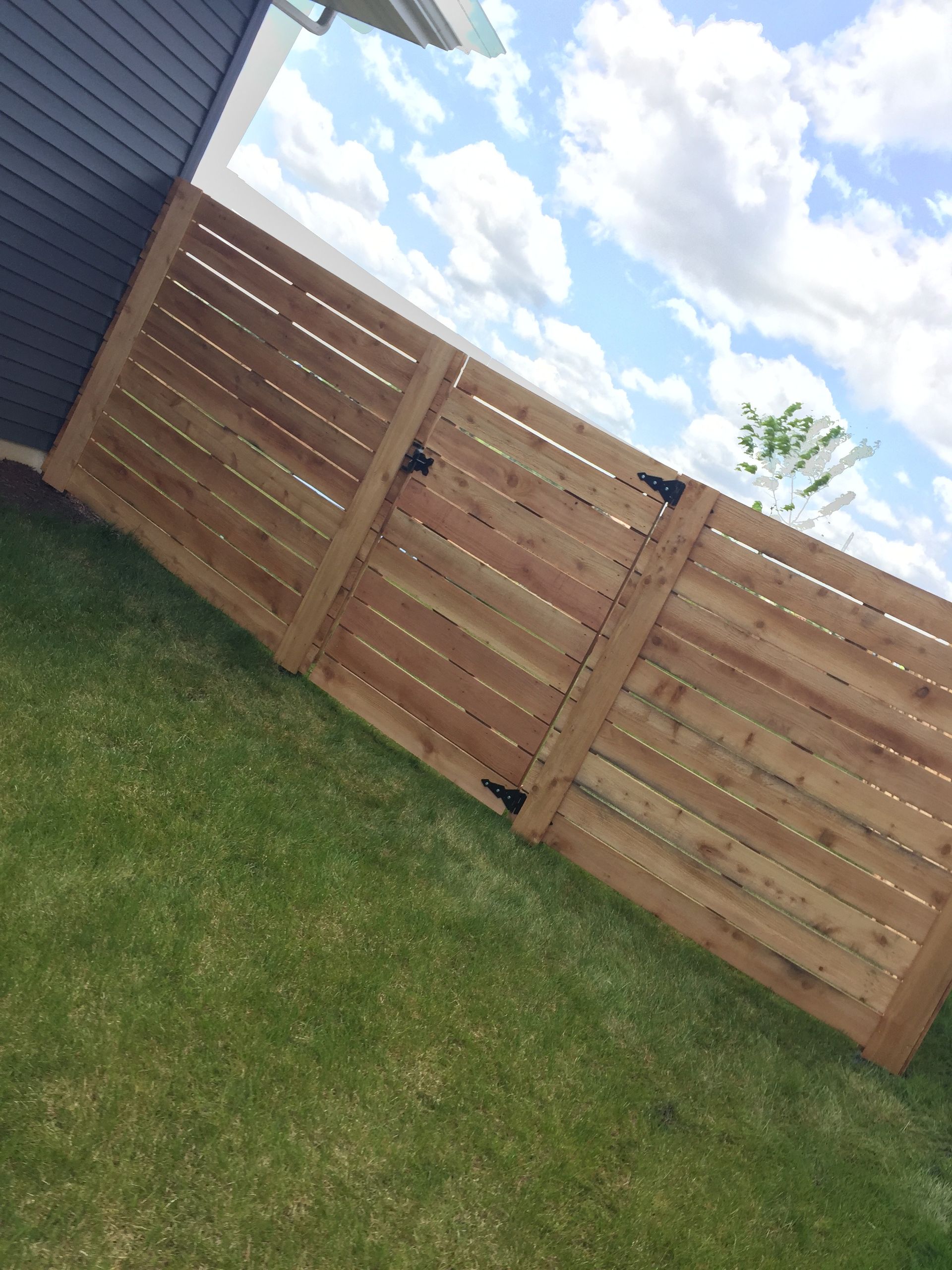 A wooden fence with a gate in the backyard of a house.