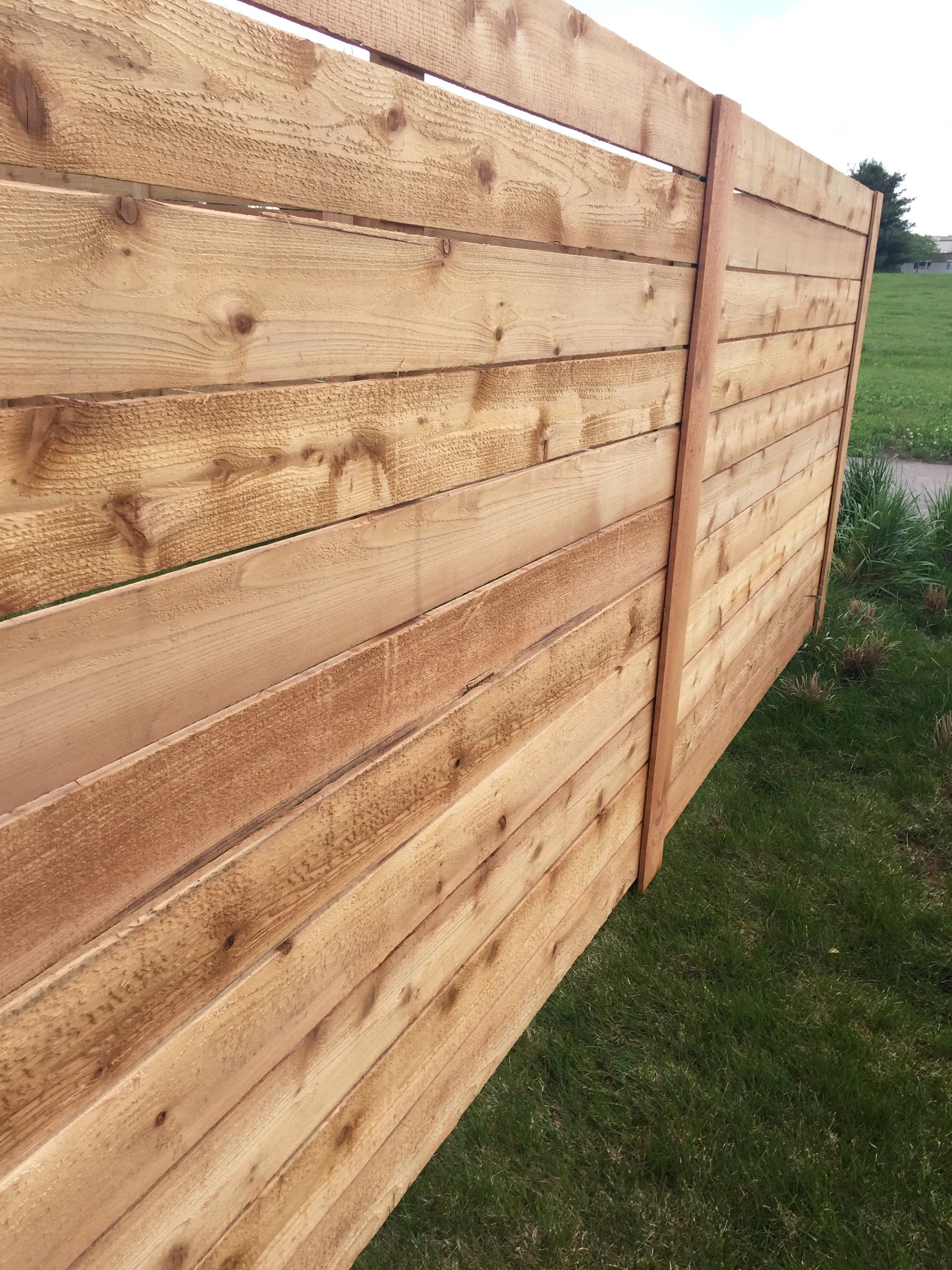 A wooden fence is sitting on top of a lush green field.