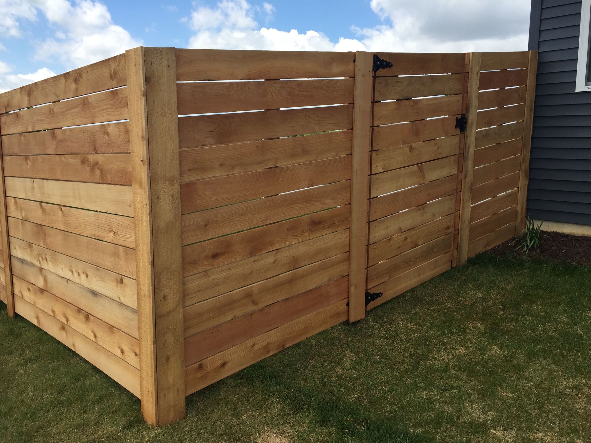 A wooden fence with a gate in front of a house.