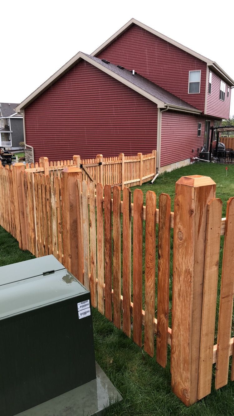 A wooden fence is in front of a red house.
