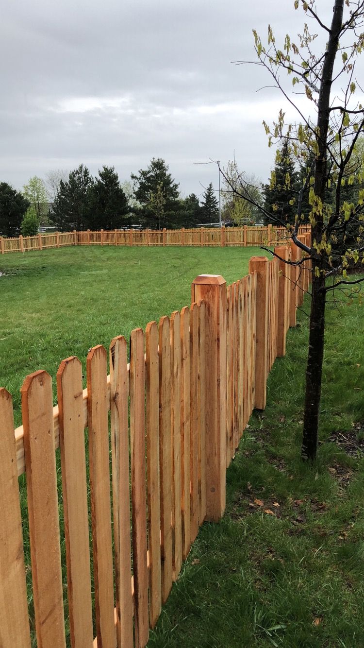 A wooden picket fence surrounds a lush green field.