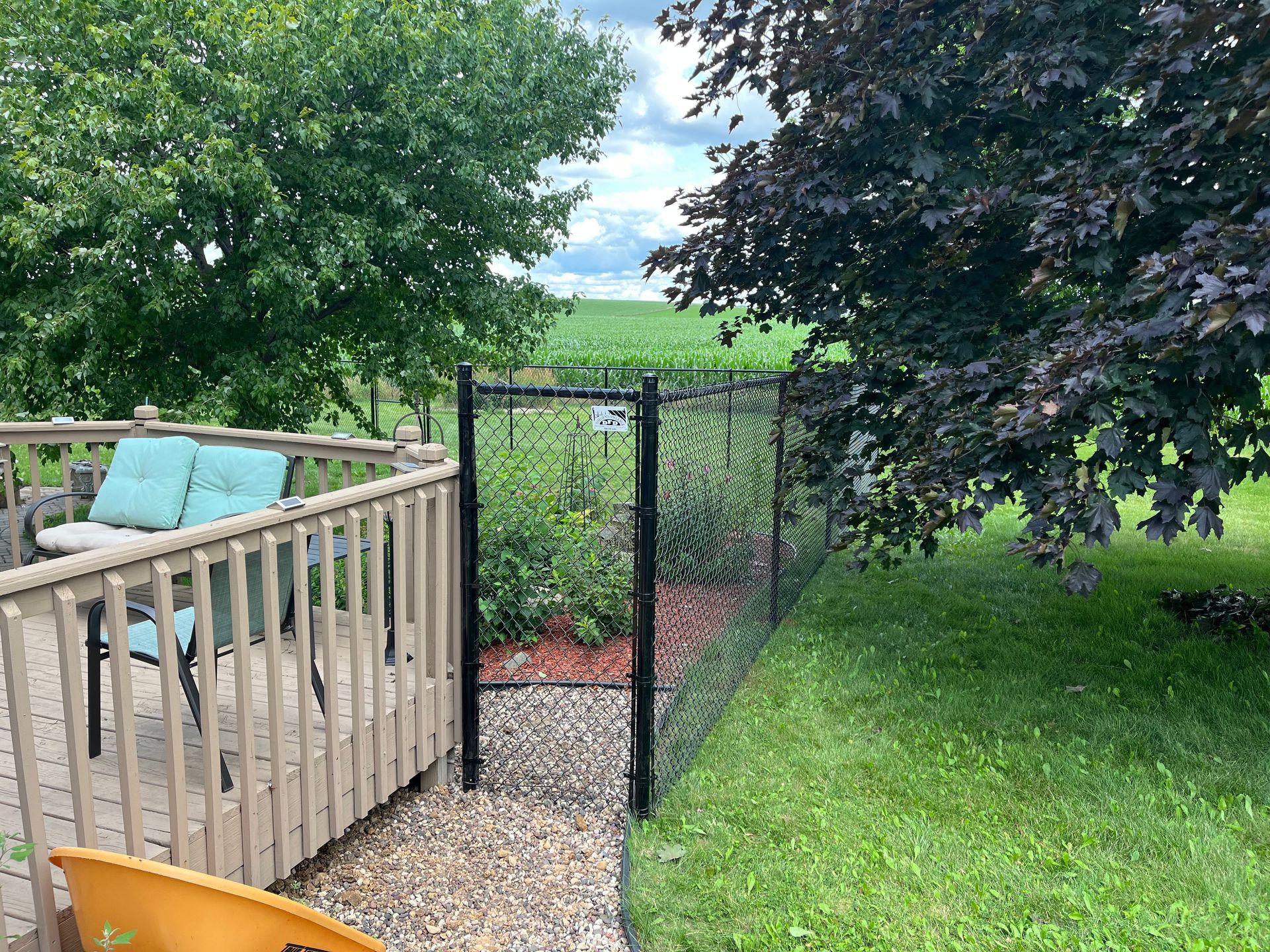 There is a deck with chairs and a fence in the backyard.