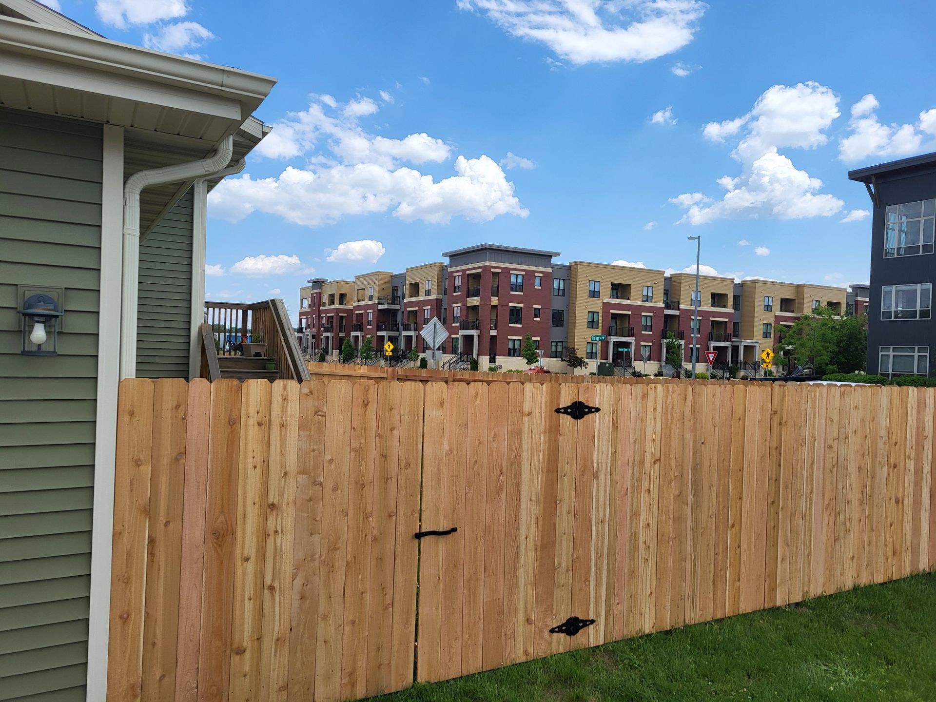 A wooden fence in front of a house with a building in the background.