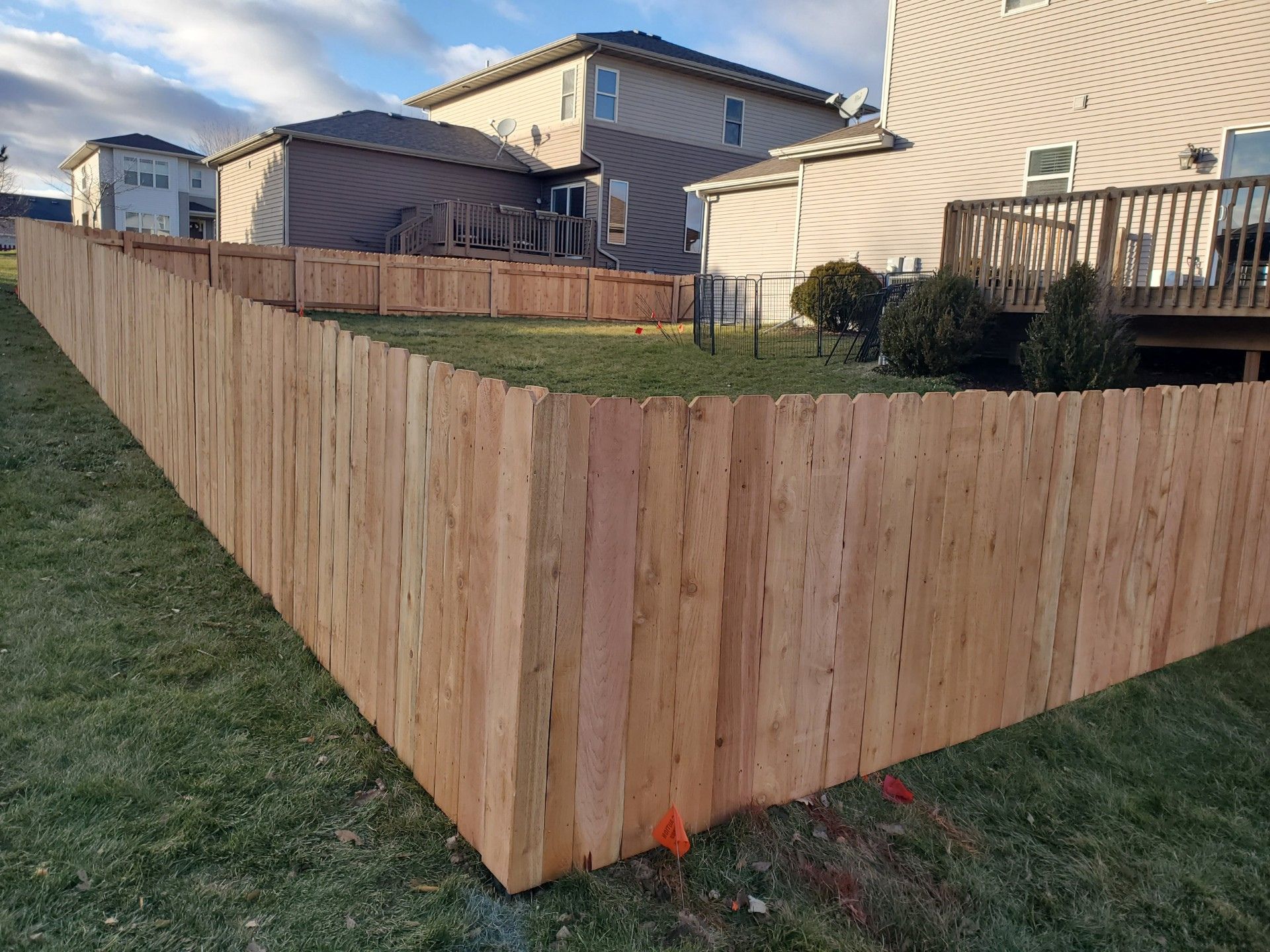 A wooden fence is in the backyard of a house.