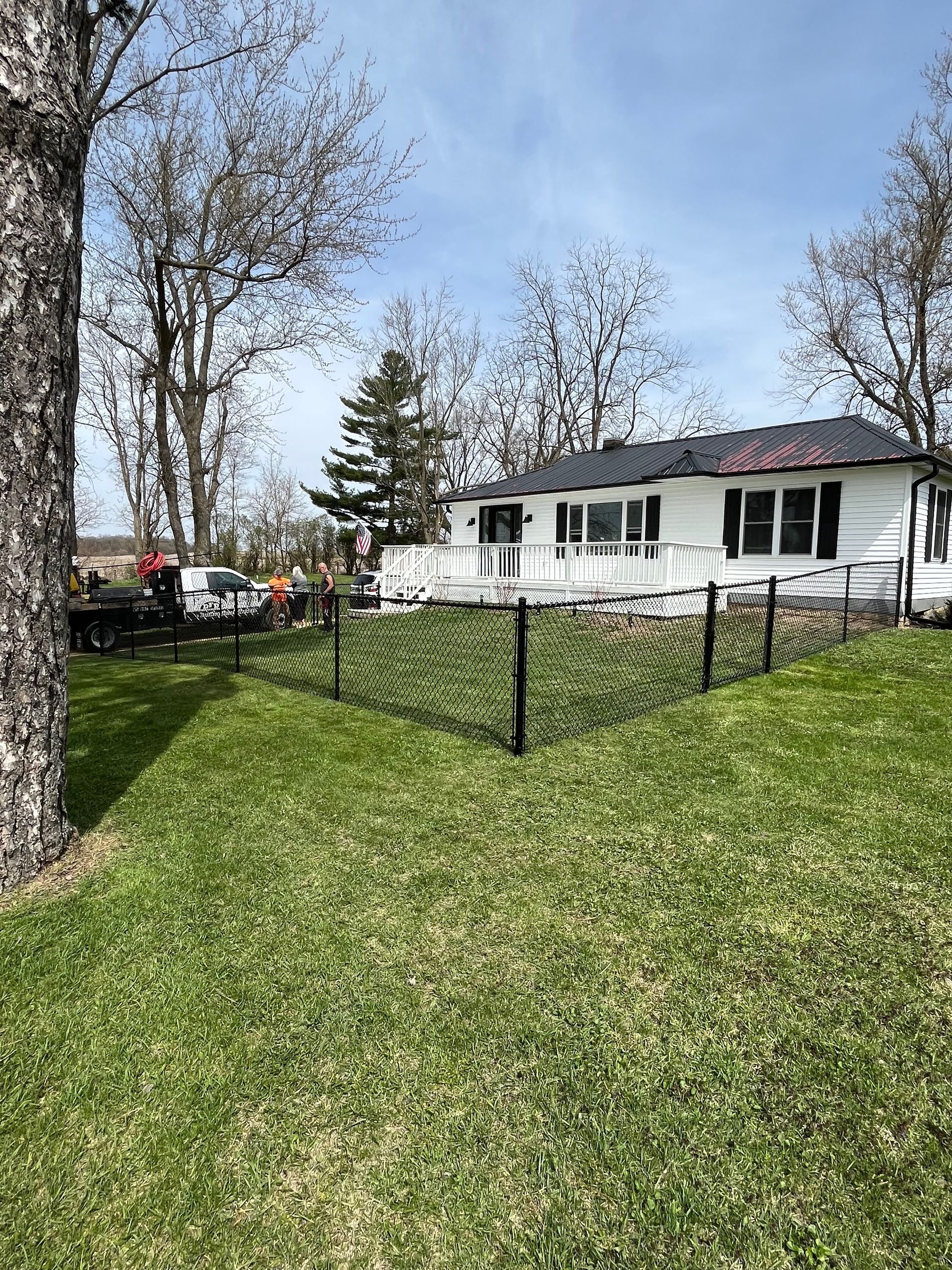 A white house is sitting on top of a lush green hill surrounded by trees.