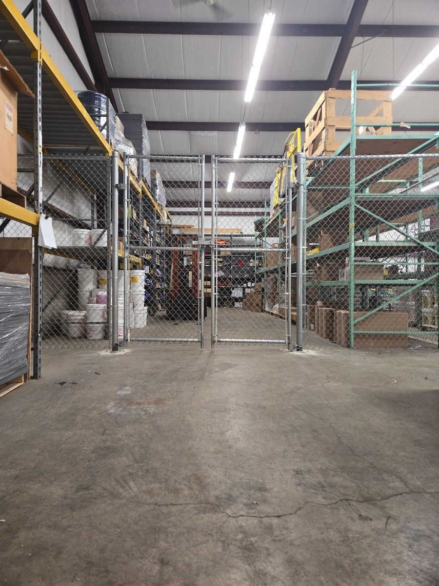 An empty warehouse with a chain link fence and shelves.