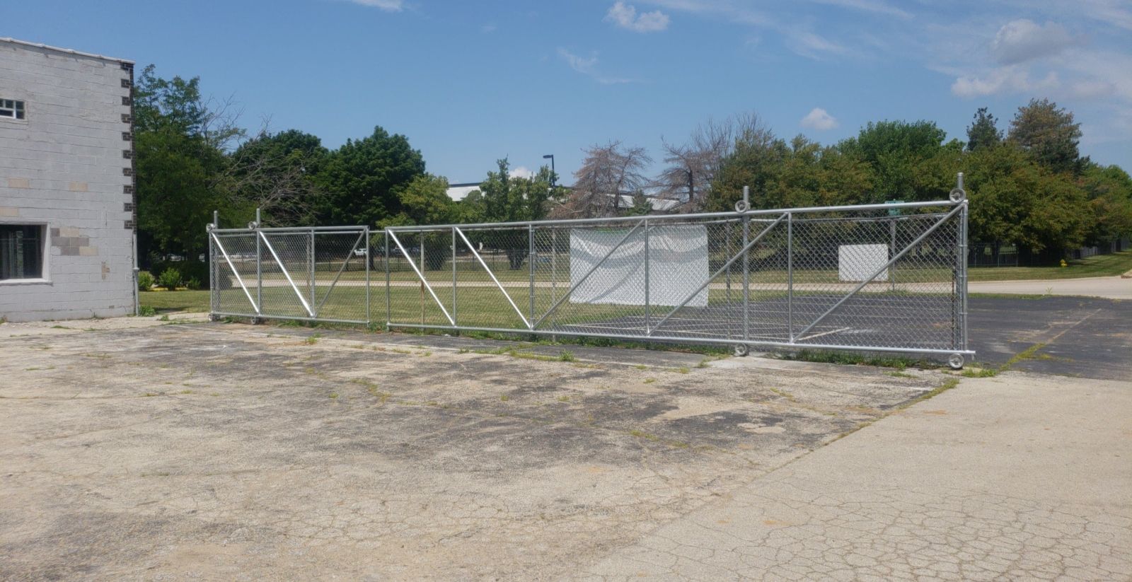 A large metal fence is surrounding a dirt field.