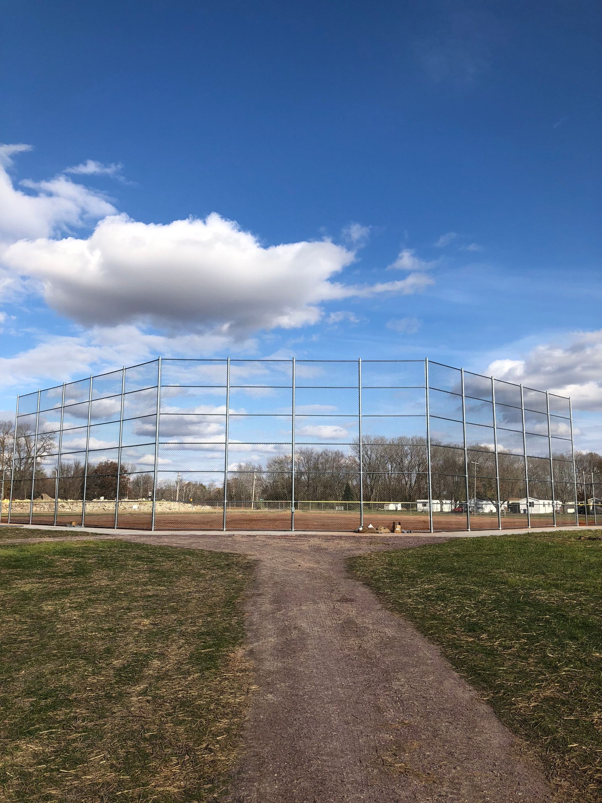 There is a dirt path leading to a baseball field.