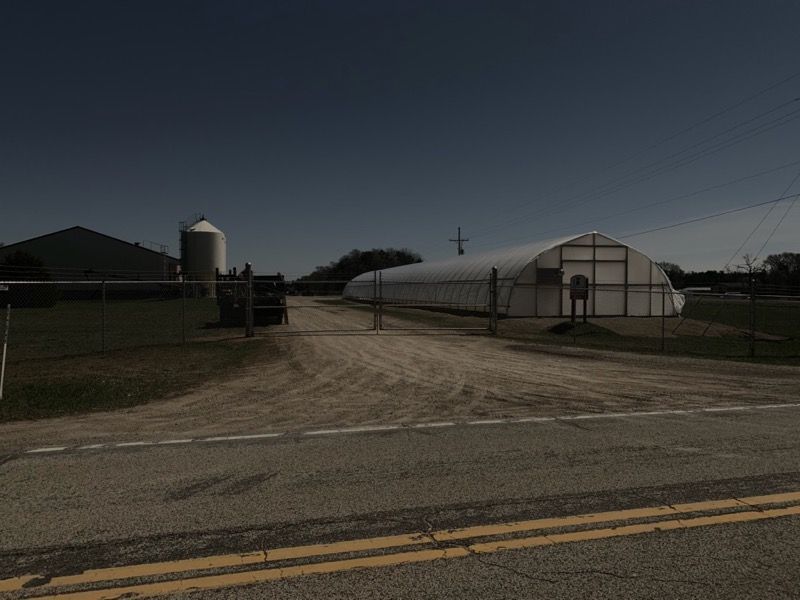 A dirt road leading to a greenhouse on a farm