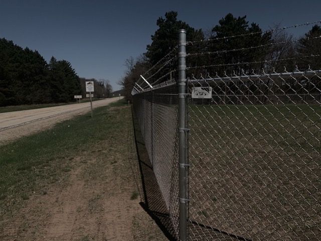 A chain link fence along the side of a dirt road
