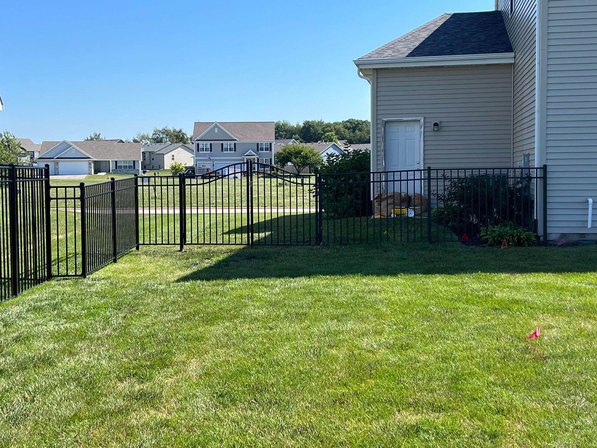 A backyard with a fence and a house in the background.