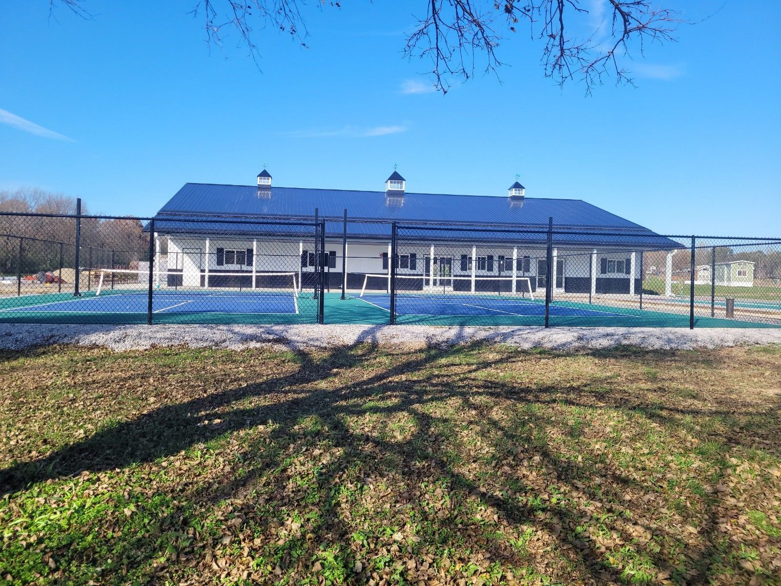 A large white building with a tennis court in front of it.