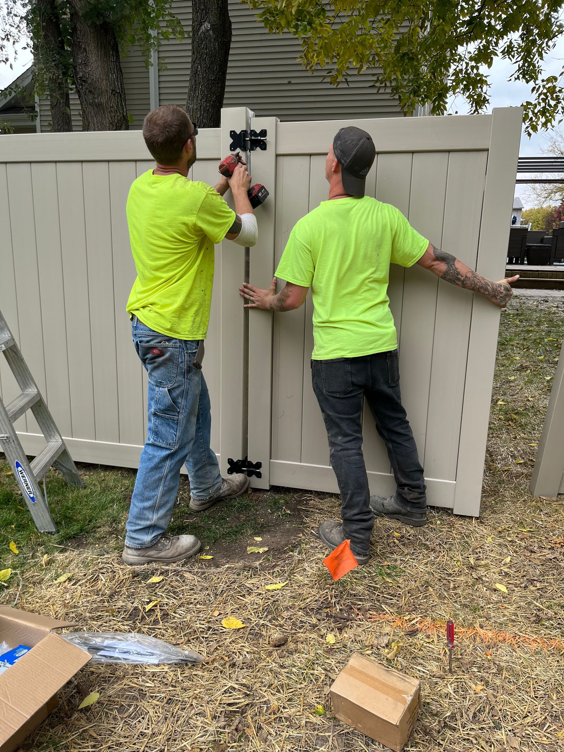 Two men are installing a gate on a fence.