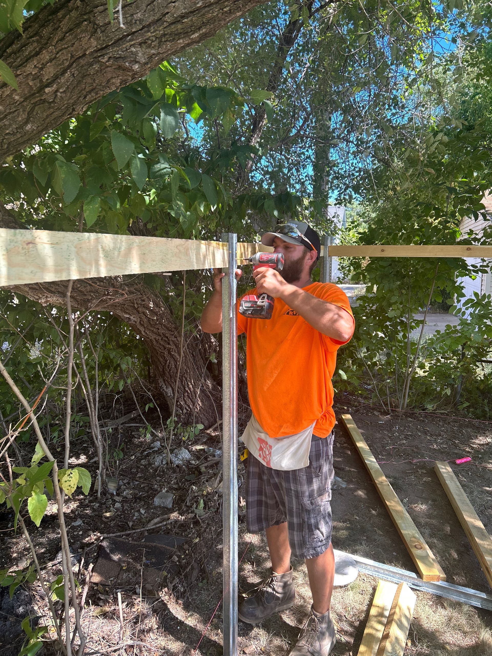 A man is working on a fence with a drill.