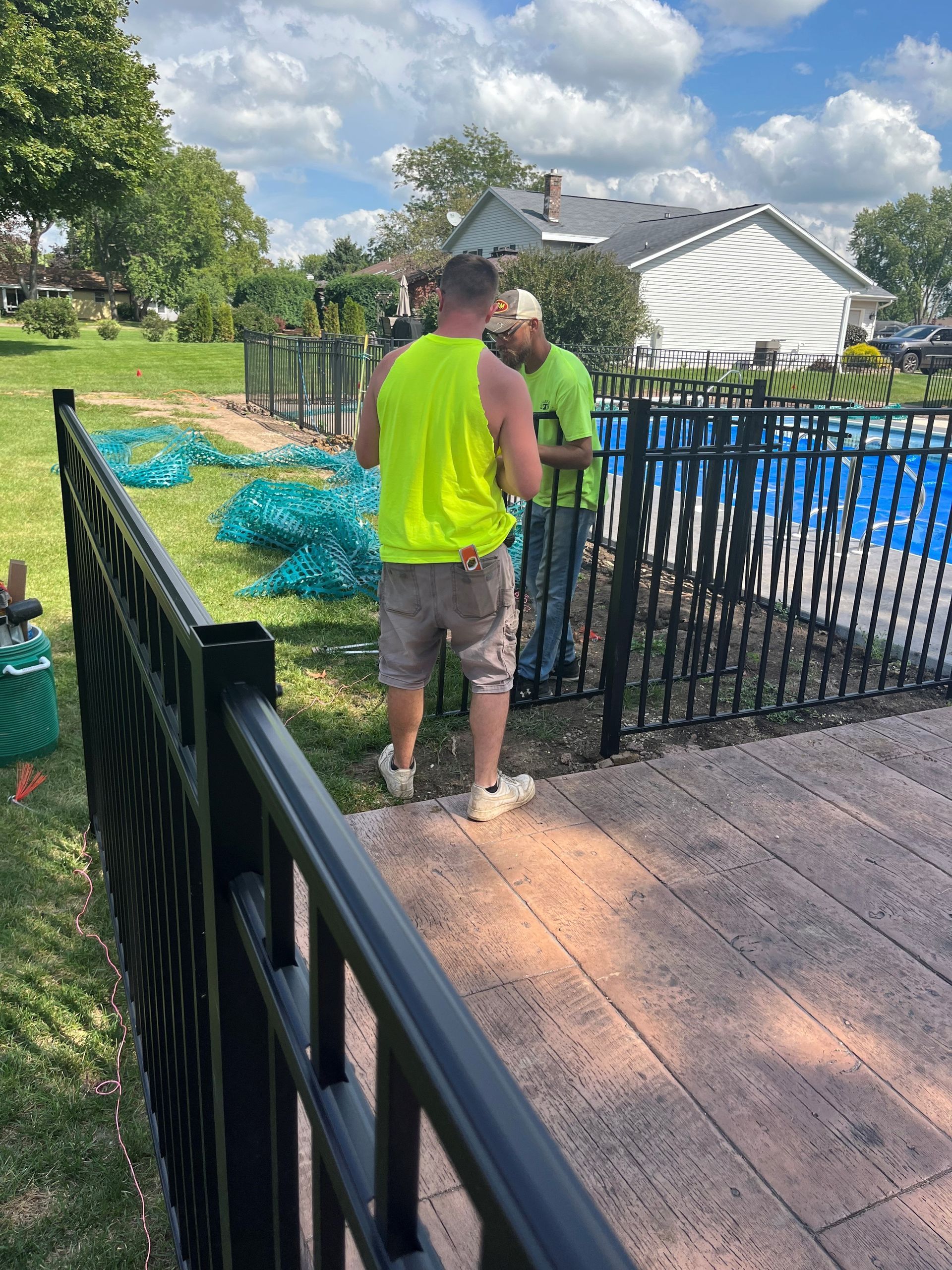 A group of men are working on a fence around a pool.