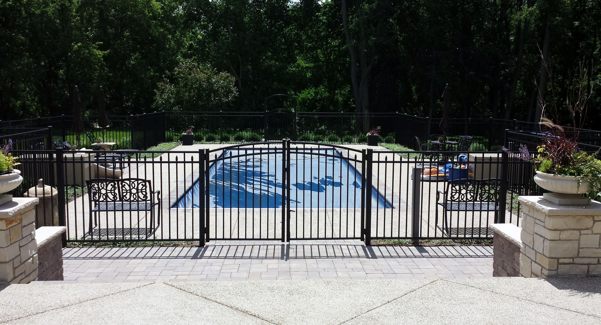 A black fence surrounds a large swimming pool