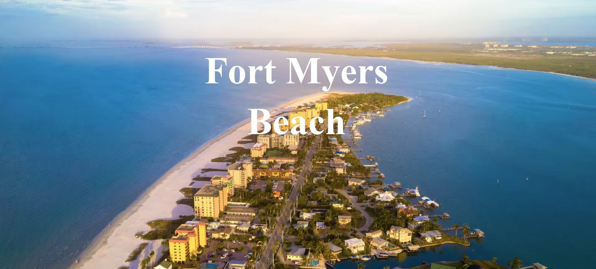 Aerial view of Fort Myers Beach, Florida, with buildings and sandy shoreline along a narrow strip of land surrounded by water.