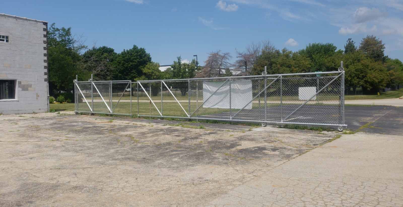 A chain link fence with a sliding gate in front of a building