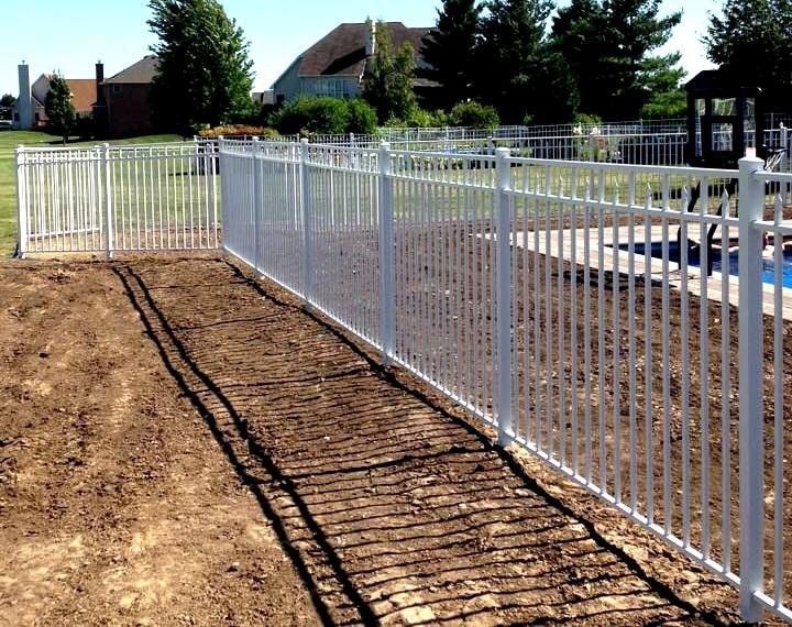 A white fence surrounds a swimming pool in a backyard