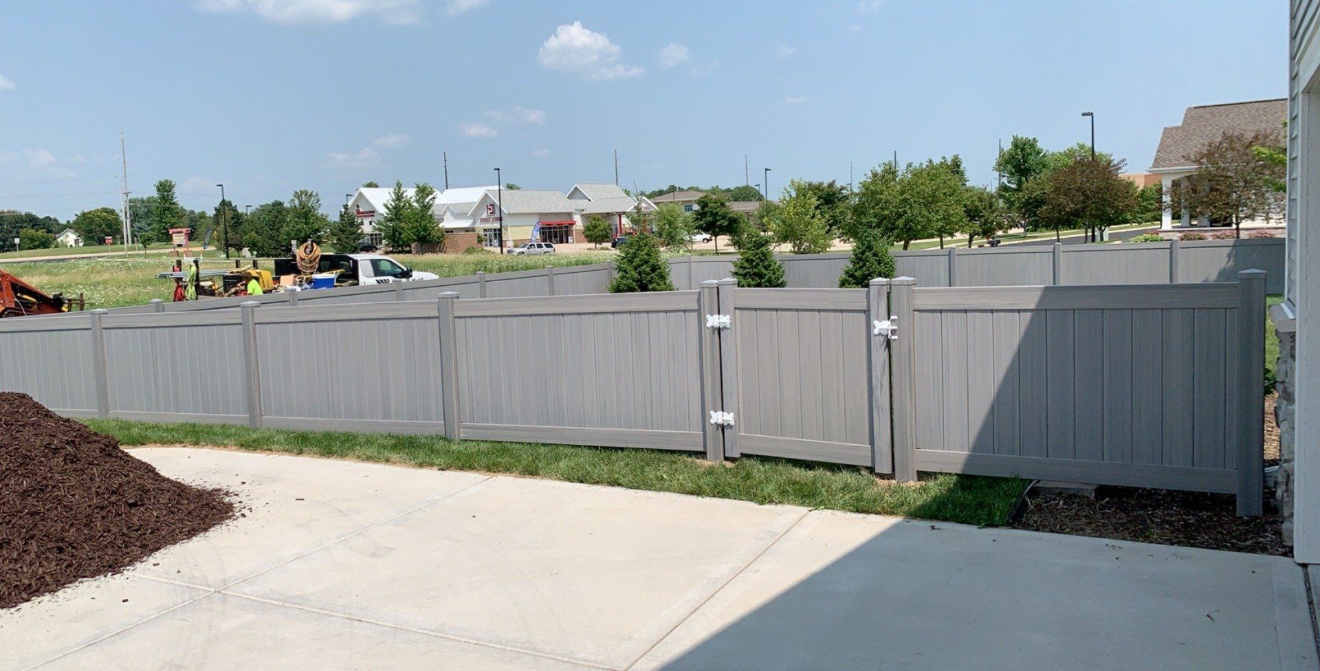 A gray fence with a gate in the backyard of a house.