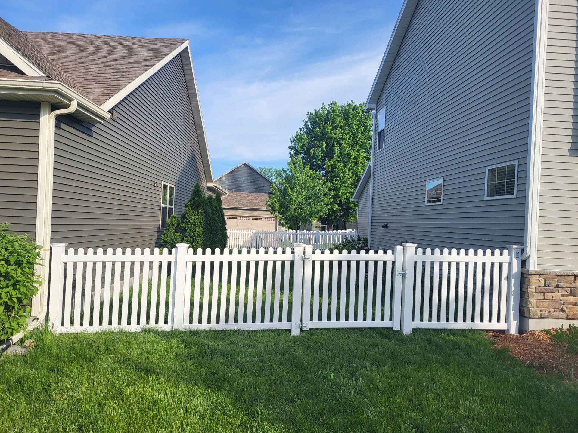 There is a white picket fence between two houses.