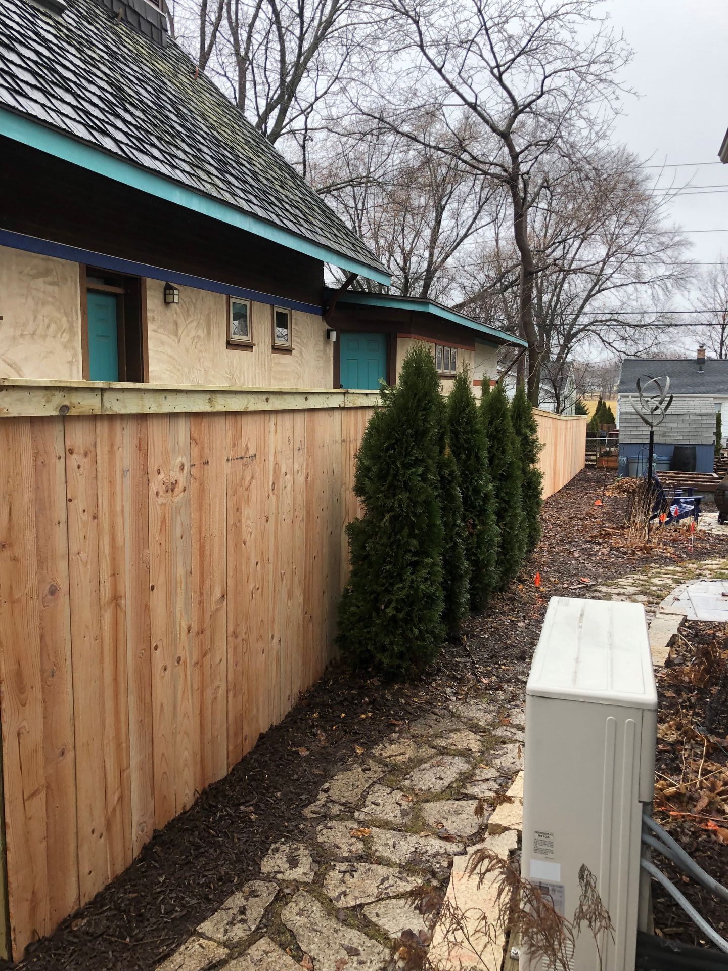 A wooden fence surrounds a building with trees in front of it.
