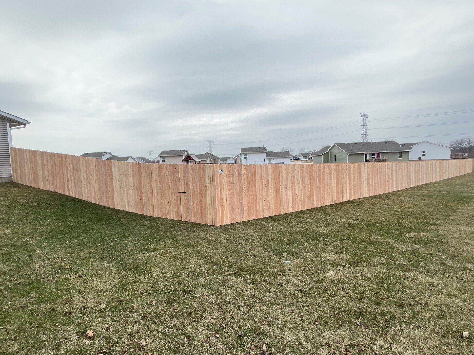 A wooden fence is in the middle of a grassy field.