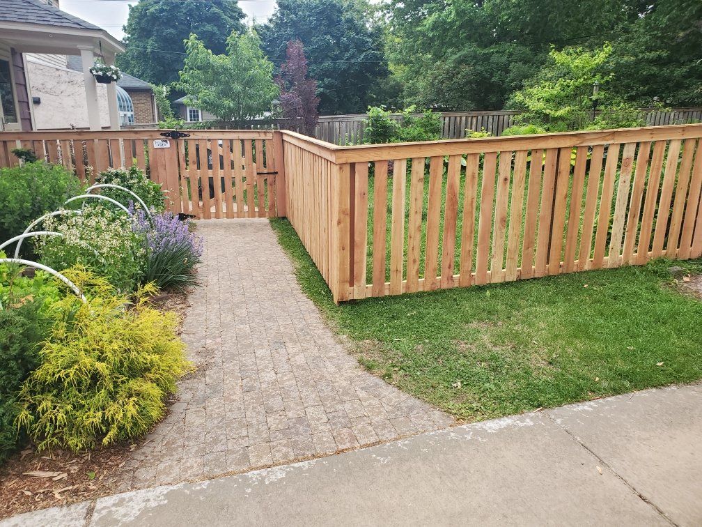 A wooden fence with a gate in the middle of a yard.
