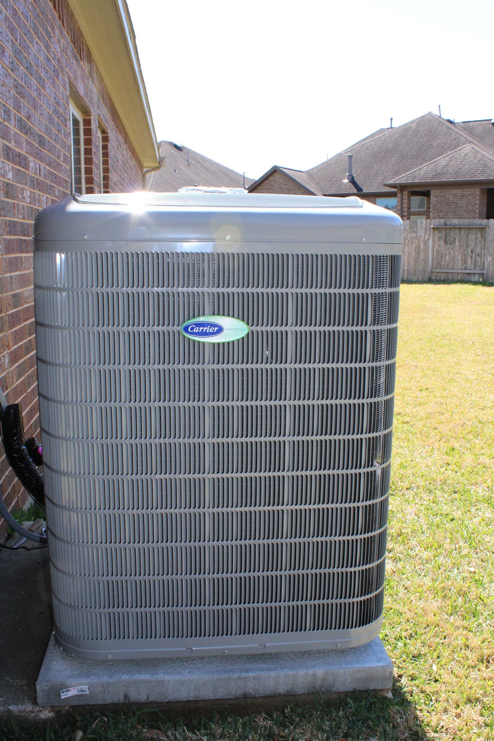 An air conditioning unit against a brick building on a sunny day.