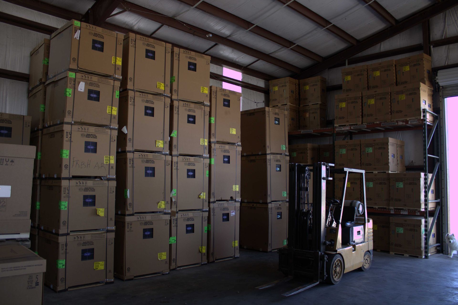 Forklift in a warehouse with stacked boxes.