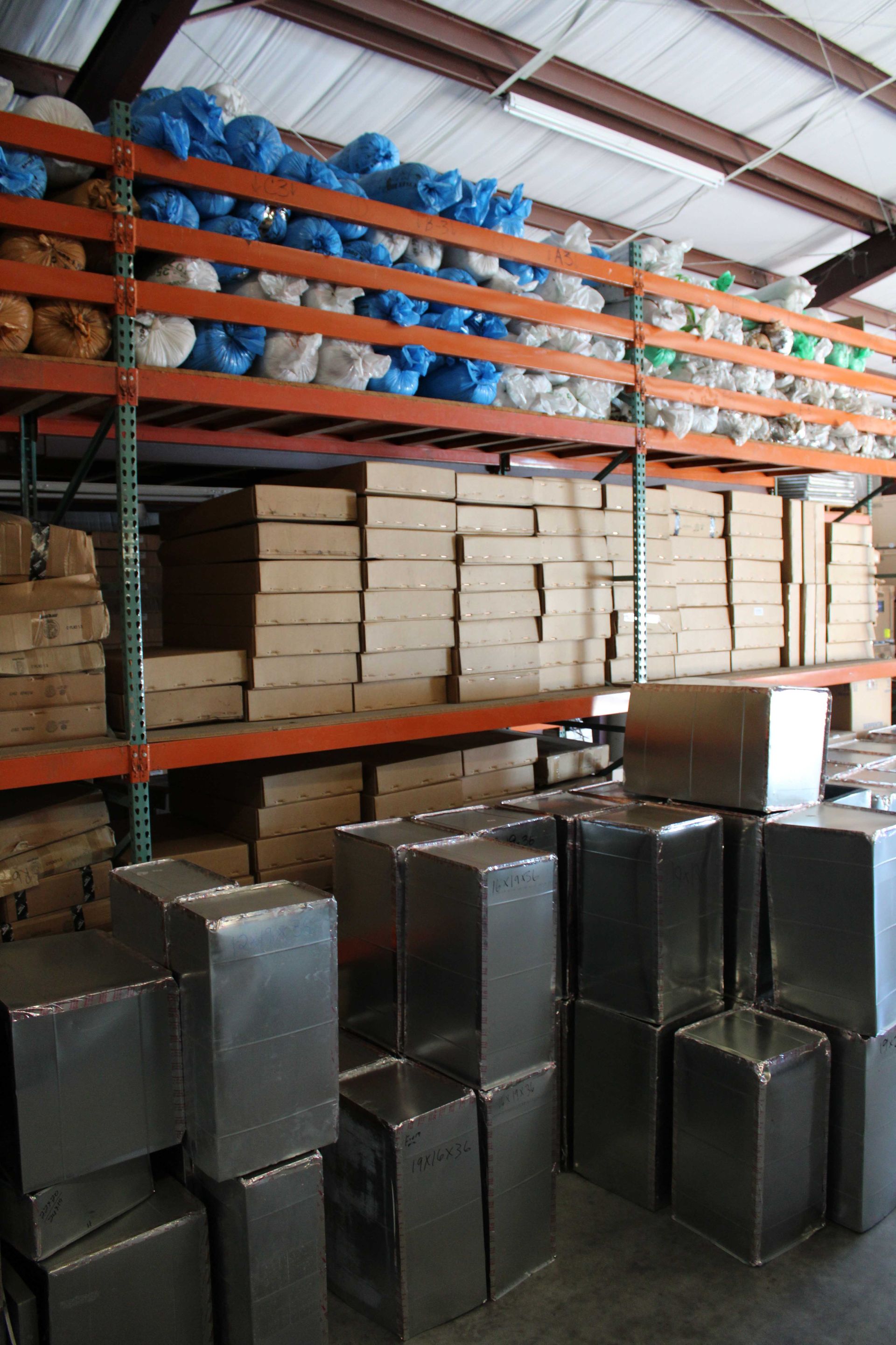 Warehouse with metal containers, boxes, and items in blue and white on shelves.