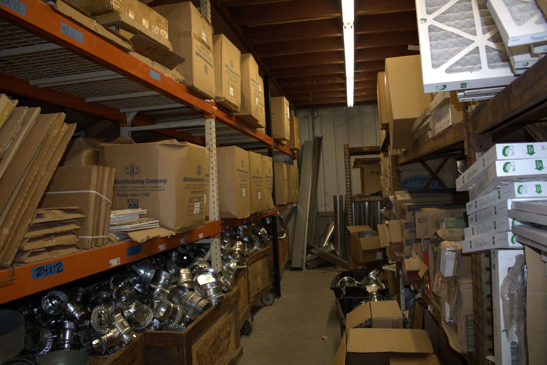 Warehouse interior with shelves of cardboard boxes and metal fixtures.