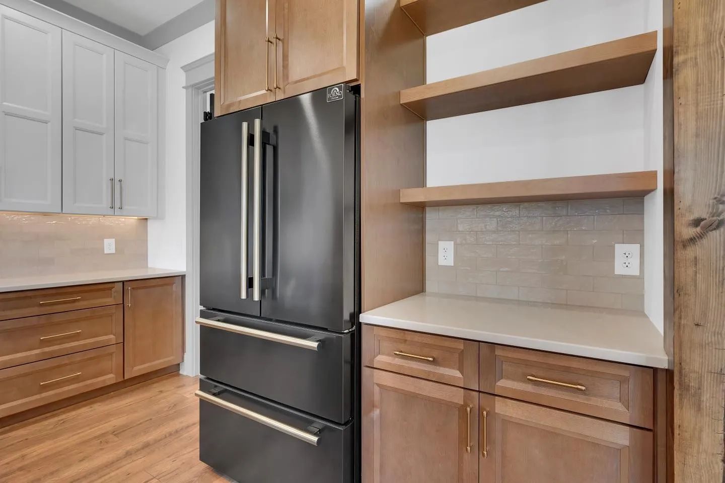 Modern kitchen corner with stainless steel fridge, wood cabinets, and open shelves