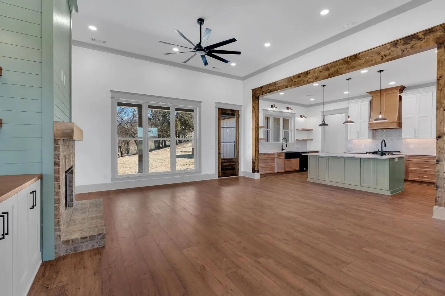 Open-plan living room with wood floors, exposed beams, and a white kitchen island