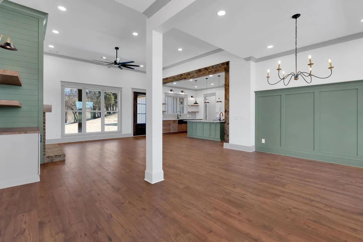 Bright open living room with hardwood floors, mint built-ins, kitchen island, and chandelier.