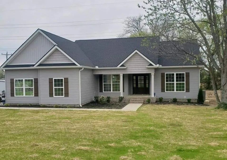 Single-story gray house with white trim and a front porch on a grassy lot